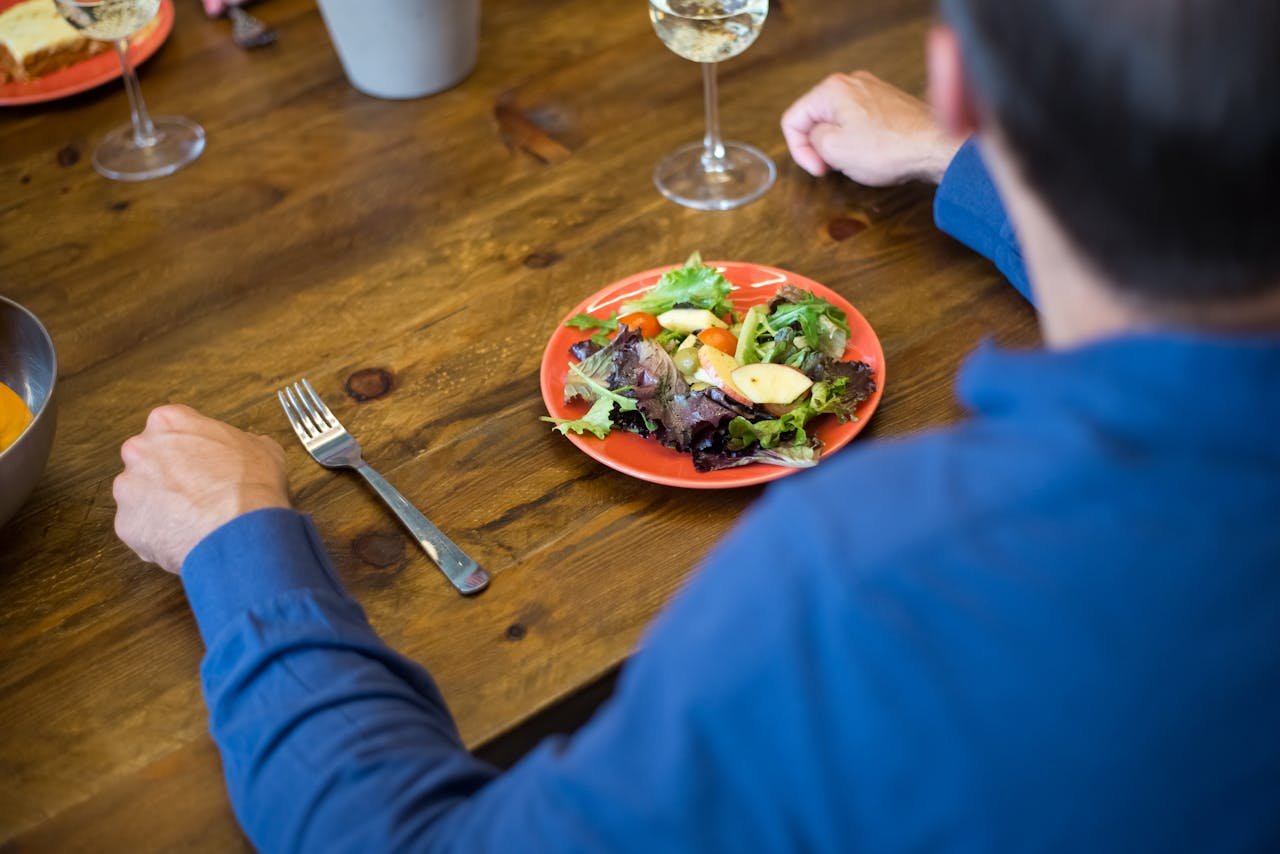 why-choose-us Person in blue enjoys a fresh salad at a rustic wooden table, Portugal.